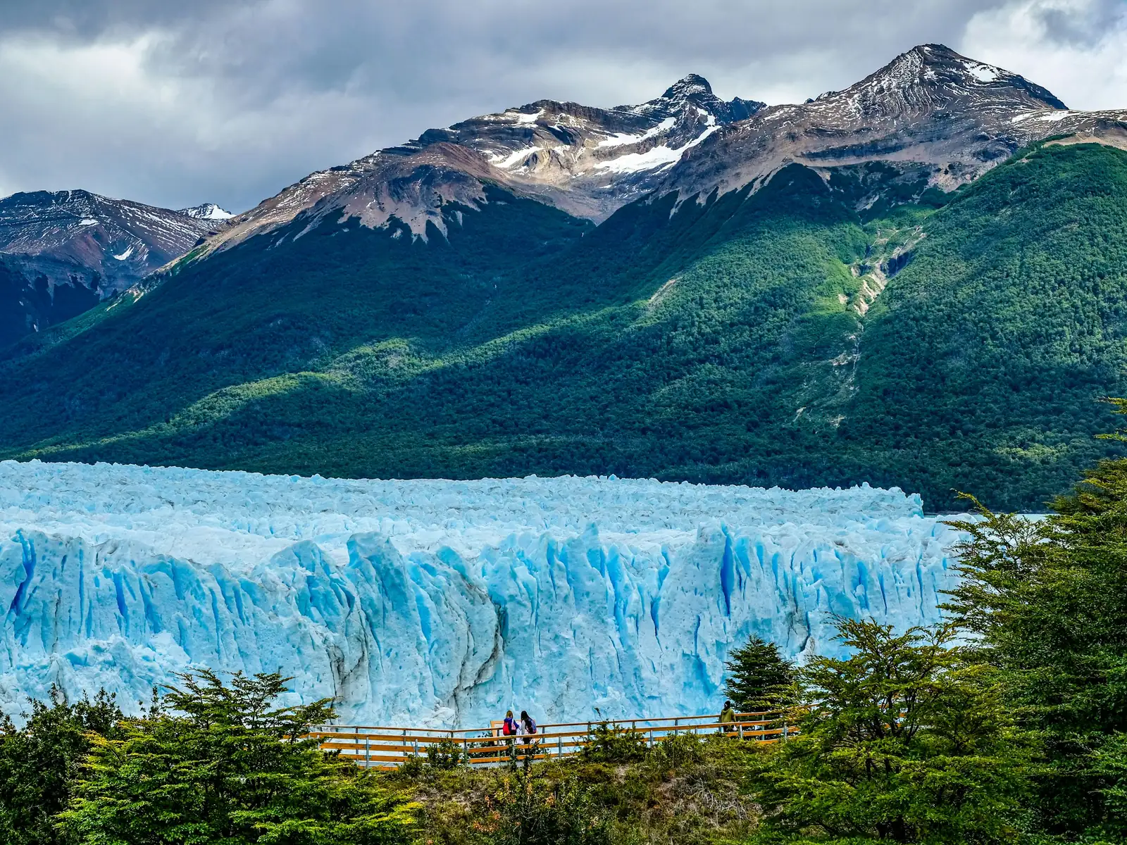 The blue ice wall of the Perito Moreno glacier below Patagonian mountains