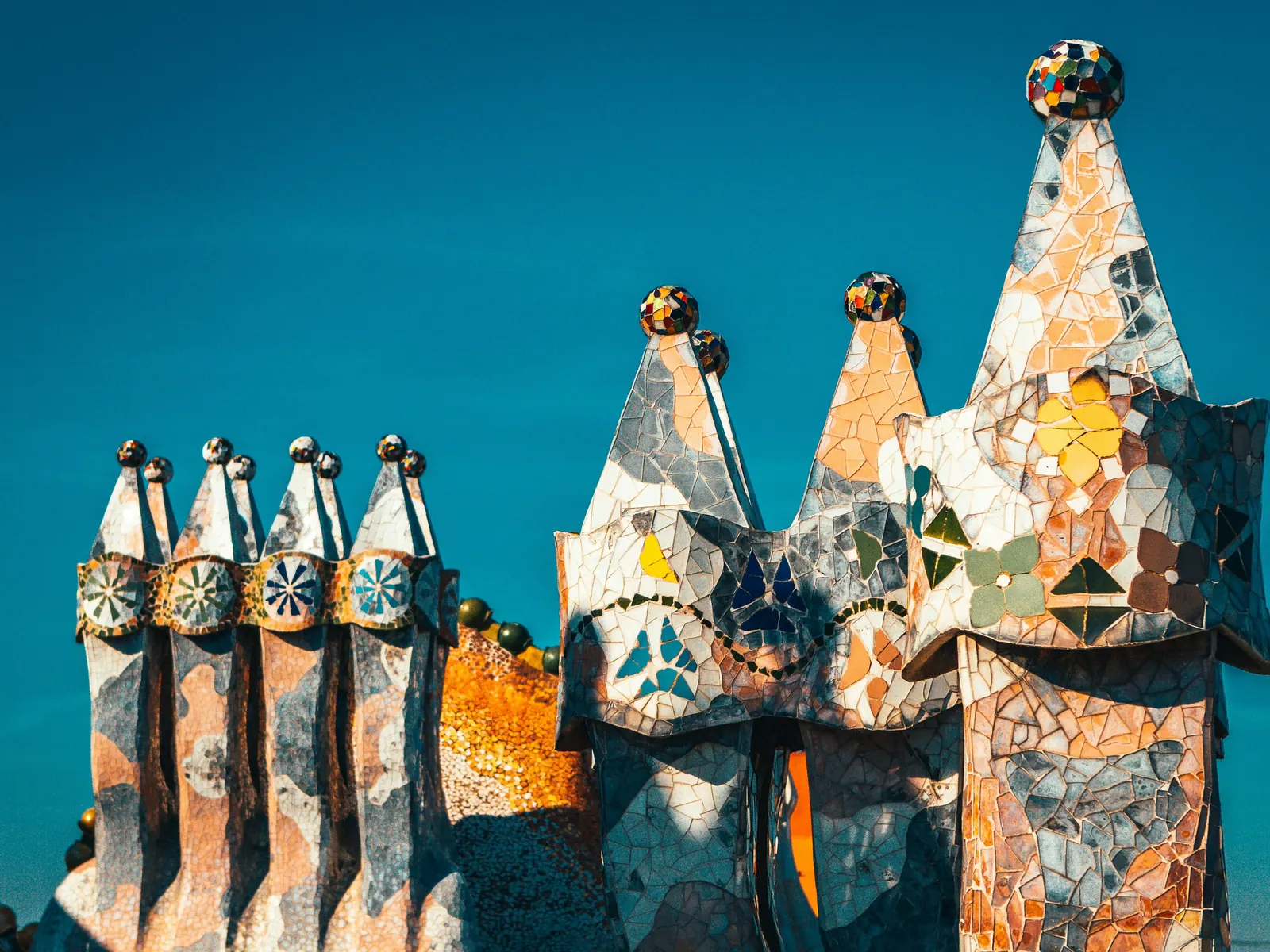 Trencadís mosaic rooftop chimneys of Casa Batlló against a blue sky