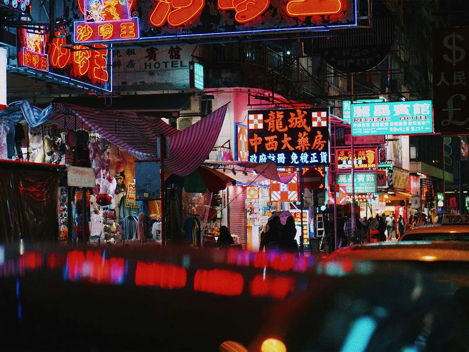 Glowing neon shop signs above a Hong Kong street at night